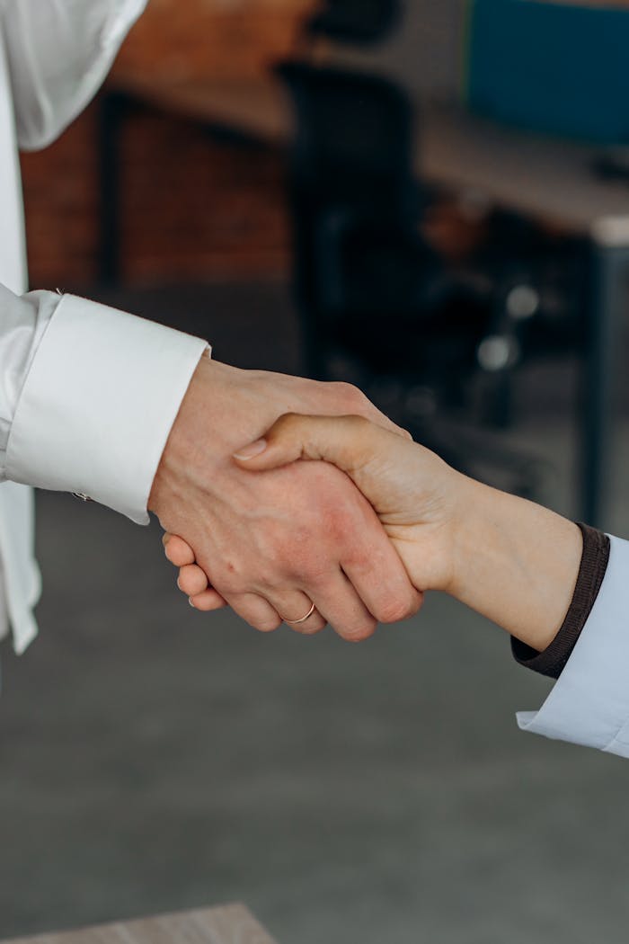 Close-up shot of two people's hands shaking, symbolizing partnership or agreement in an office setting.